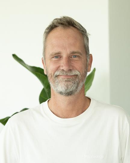 Portrait of me, smiling, in a white T-shirt.
